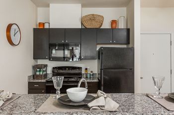 a kitchen with black appliances and a table with a bowl on it at 310 at Nulu Apartments-Student, Louisville, KY 40202